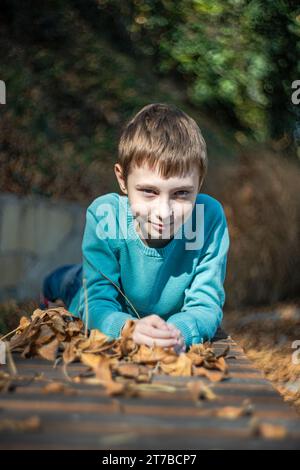 Portrait d'un garçon appuyé sur ses bras sur une table dans un parc automnal, Géorgie Banque D'Images