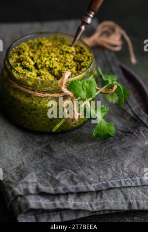 Savoureux adjika vert dans le pot en verre plat traditionnel de Géorgie Banque D'Images