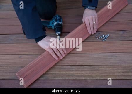 Installation de terrasse mains de charpentier tenant la planche de nettoyage, terrasse terrasse travaux de construction en bois Banque D'Images