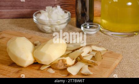 Éplucher et couper les pommes de terre. Recette de soupe de légumes. Gros plan sur les légumes frais crus sur fond rustique Banque D'Images