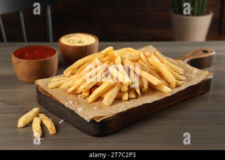 Délicieuses frites servies avec des sauces sur une table en bois Banque D'Images