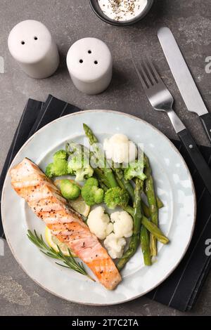 Repas sain. Morceau de saumon grillé, légumes, asperges et romarin servi sur une table texturée grise, plat Banque D'Images