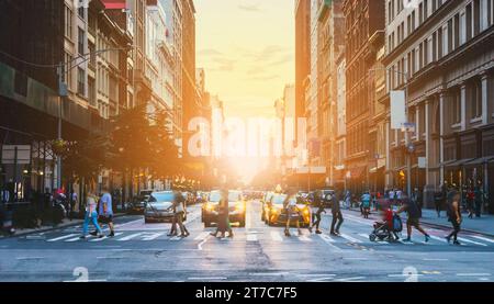 Foules de personnes, de voitures et de taxis dans l'intersection animée de la 23rd Street et de la 5th Avenue à New York avec la lumière du soleil en arrière-plan Banque D'Images