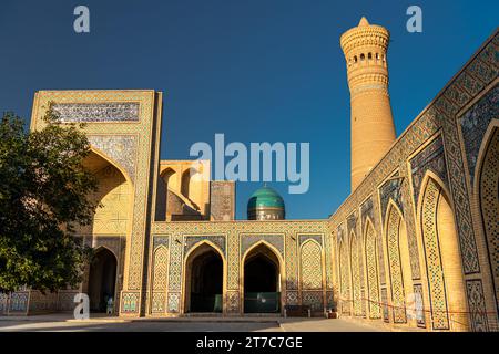 Ensemble architectural (12e siècle), minaret et mosquée. Boukhara, Ouzbékistan. Cour intérieure de la mosquée, ciel de coucher de soleil avec espace de copie pour le texte Banque D'Images