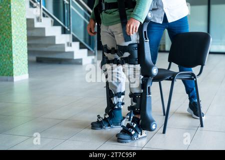 Exosquelette mécanique, physiothérapeute a aidé une personne handicapée à se lever avec un squelette robotique, physiothérapie dans un hôpital moderne: Banque D'Images