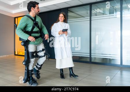 Exosquelette mécanique, physiothérapeute médecin femme marchant avec une personne handicapée aidée par un squelette robotique, physiothérapie dans un hôpital moderne Banque D'Images