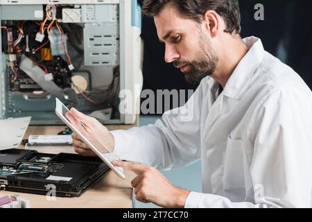 Technicien masculin de vue latérale utilisant la tablette numérique Banque D'Images