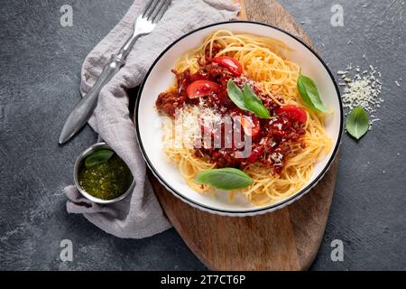 Savoureuses pâtes italiennes classiques spaghetti bolognaise appétissantes avec sauce tomate, parmesan au fromage, viande et basilic sur une assiette sur fond sombre. Vue de dessus. Banque D'Images