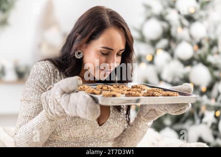 Femme sent les biscuits aux pépites de chocolat fraîchement cuits pour les vacances de Noël. Banque D'Images