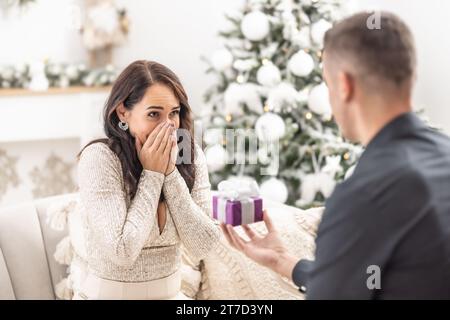 Petit ami surprend sa petite amie avec une proposition pour les éternuements de Noël devant elle. Banque D'Images