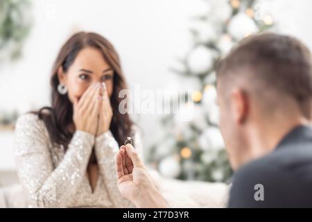 Proposition de Noël d'un homme tenant une bague devant sa petite amie surprise. Banque D'Images