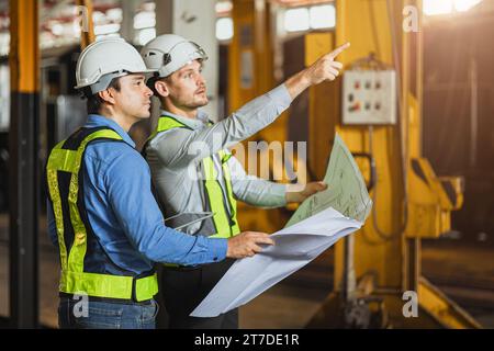 Ingénieur en construction avec l'équipe de concepteur de technicien travaillant chantier inspecter pour rénover l'intérieur dans le bâtiment d'atelier d'industrie avec plan d'étage. Banque D'Images