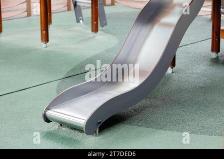curseur de terrain de jeu en gros plan pour les enfants qui jouent en glissant vers le bas sur le sol en pierre de caoutchouc souple de sécurité. Banque D'Images
