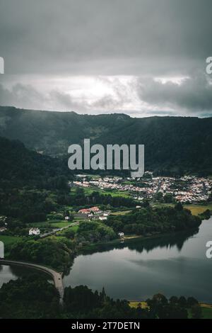 Une vue panoramique sur une ville entourée de collines verdoyantes et d'eaux tranquilles. Lagune de Sete Cidades, Sao Miguel Banque D'Images