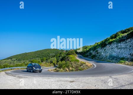 Une voiture négocie un virage en épingle à cheveux sur la route Lakones Makrades Vistonas à Agia Anna, Corfou, Grèce Banque D'Images