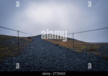 Vue aérienne d'une route sinueuse serpentant à travers un paysage rocheux, avec des lignes électriques traversant le terrain Banque D'Images