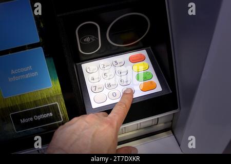 Gros plan de la main d'une personne pressant une carte de crédit dans un distributeur automatique de billets Banque D'Images
