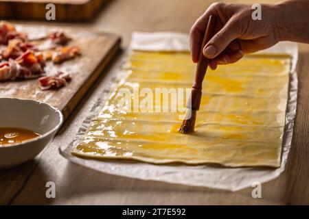 Une cuisinière féminine badigeonne la pâte feuilletée avec l'œuf. Procédure de recette : 1 de 10 Banque D'Images