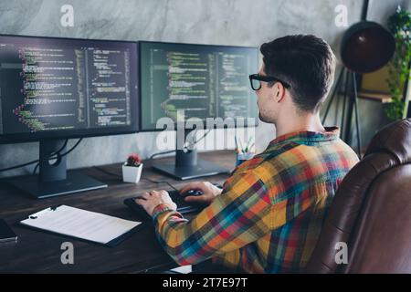 Photo de vue arrière de l'homme de travailleur à distance axée sur la création parfaite d'analyse de données automatique code bot assis fauteuil au bureau à domicile Banque D'Images