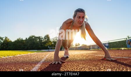 Athlète féminine déterminée en position de départ sur piste de course Banque D'Images
