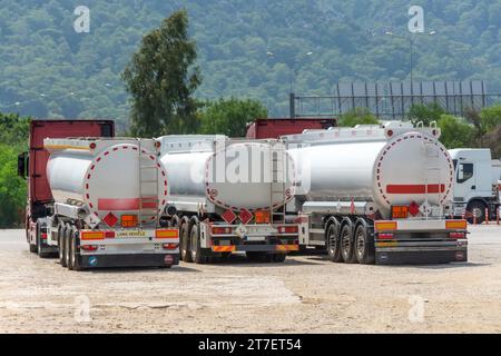 Stationnement rangée de camions avec réservoirs de carburant en face d'un entrepôt et stockage d'énormes réservoirs de conteneurs de matières premières, à côté de l'autoroute principale. Banque D'Images