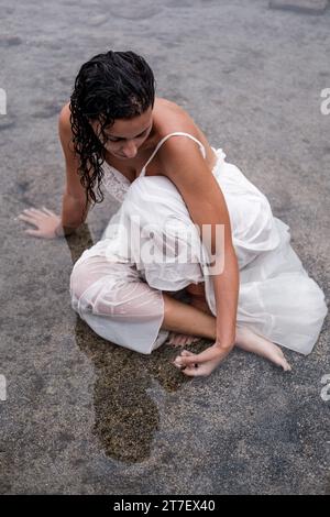 Une femme brune en costume blanc profite d'un moment de détente en profitant des thérapies à l'eau de mer Banque D'Images