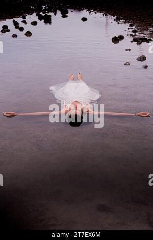 Une femme brune en costume blanc profite d'un moment de détente en profitant des thérapies à l'eau de mer Banque D'Images