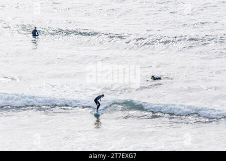 Coastal Harmony : vue aérienne de trois surfeurs Créer une pose triangulaire, Riding vagues avec précision et unité Banque D'Images