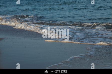 Une grande et forte onde de tempête de couleur turquoise avec des éclaboussures de mousse blanche coule et se brise sur le rivage. Banque D'Images