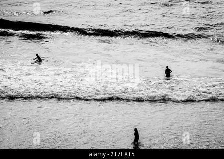 Coastal Harmony : vue aérienne de trois surfeurs Créer une pose triangulaire, Riding vagues avec précision et unité Banque D'Images