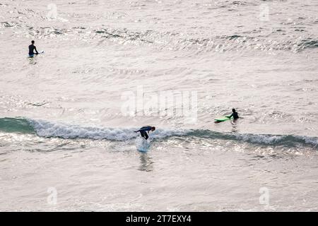 Coastal Harmony : vue aérienne de trois surfeurs Créer une pose triangulaire, Riding vagues avec précision et unité Banque D'Images