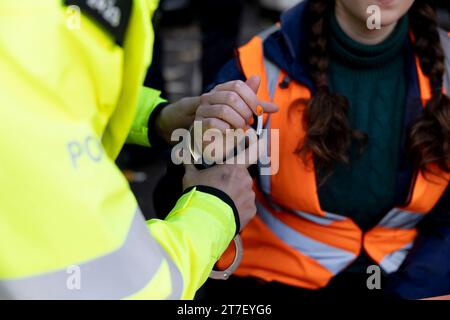 Londres, Royaume-Uni. 15 novembre 2023. Un manifestant est menotté par la police du met pour avoir bloqué la circulation pendant la manifestation dans le centre de Londres. Les militants étudiants de Just Stop Oil manifestent sur Cromwell Road à Earls court tôt ce matin à l'heure de pointe dans le cadre de leurs marches lentes de trois semaines. Le groupe appelle le gouvernement britannique à mettre fin à toutes les futures licences de combustibles fossiles et promet de poursuivre ses actions jusqu'à ce que cela se produise. Crédit : SOPA Images Limited/Alamy Live News Banque D'Images