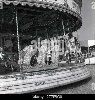 Années 1970, historique, adultes et enfants chevauchant sur un manège ou un carrousel à une foire funéraire, Angleterre, Royaume-Uni. Banque D'Images