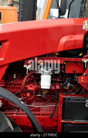 Gros plan d'une partie du nouveau tracteur rouge. Assemblage de véhicule. Banque D'Images