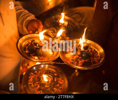 Une main d'homme tenant 4 lampes diya à huile à ganga aarti à Rishikesh Banque D'Images