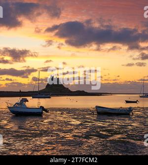 Lever de soleil en été sur le château de Lindisfarne sur l'île Sainte de Lindisfarne dans le Northumberland vu du port Banque D'Images