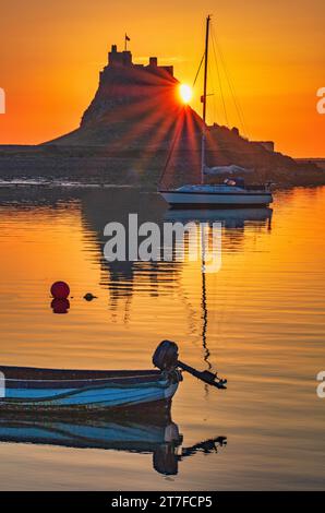 Lever de soleil en été sur le château de Lindisfarne sur l'île Sainte de Lindisfarne dans le Northumberland vu du port Banque D'Images