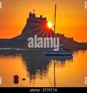 Lever de soleil en été sur le château de Lindisfarne sur l'île Sainte de Lindisfarne dans le Northumberland vu du port Banque D'Images