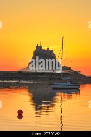 Lever de soleil en été sur le château de Lindisfarne sur l'île Sainte de Lindisfarne dans le Northumberland vu du port Banque D'Images