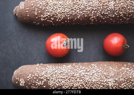 Pain intégral avec deux tomates sur fond noir Banque D'Images