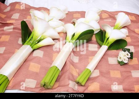 trois bouquets d'orchidées pour un mariage assis dans une rangée et placé sur le lit Banque D'Images
