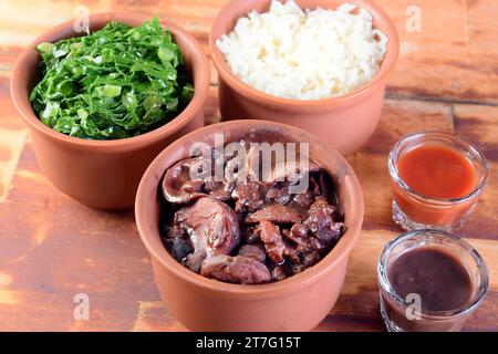 Cuisine brésilienne typique feijoada à base de haricots, porc, bacon, saucisse au chou, riz, salade, épices et poivre. Banque D'Images