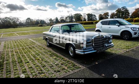Coupé Mercedes-Benz argenté classique garé dans un spacieux terrain extérieur, mettant en valeur son élégant design vintage et sa calandre chromée polie. Banque D'Images