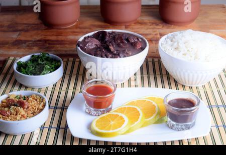 Cuisine brésilienne typique feijoada à base de haricots, porc, bacon, saucisse au chou, riz, salade, épices et poivre. Banque D'Images