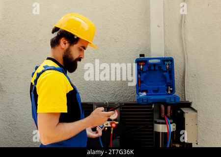 Travailleur professionnel commandant de nouvelles pièces internes pour le climatiseur défectueux après avoir terminé l'examen. Technicien agréé chargé par le client de rechercher en ligne les composants de remplacement du système hvac Banque D'Images