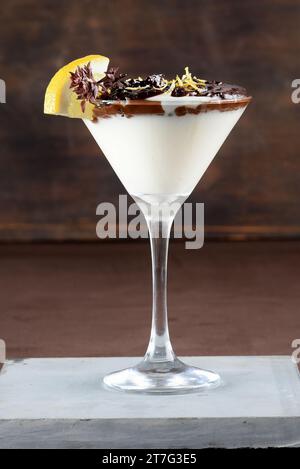 Mousse au chocolat et cheesecake superposés recouverts de chapelure de biscuit enrobé de chocolat. Dans des bols à dessert en verre. Sur le fond blanc lig crémeux Banque D'Images