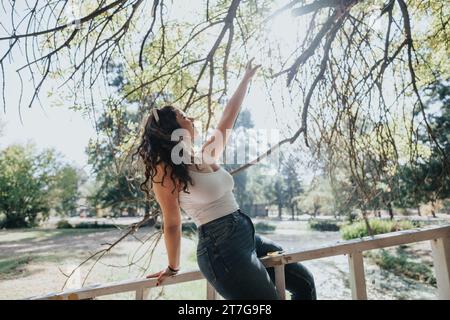 Fille dans un parc de la ville, profitant d'un week-end insouciant, imprégnant la beauté de la nature, entouré par un environnement verdoyant. Banque D'Images