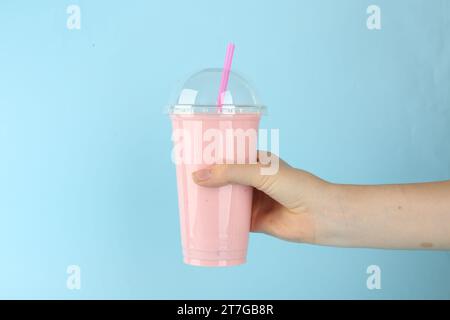 Femme avec tasse en plastique de smoothie savoureux sur fond bleu clair, closeup Banque D'Images