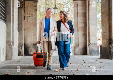 Portrait d'un couple mature heureux en visite sur un voyage romantique en Espagne. Des personnes mariées d'âge moyen marchant avec une valise. Femme et mari souriant et s'amusant lors d'une visite du week-end. Photo de haute qualité Banque D'Images