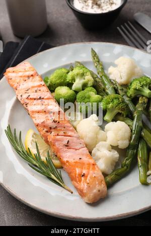 Repas sain. Morceau de saumon grillé, légumes, citron, asperges et romarin servi sur table grise, gros plan Banque D'Images